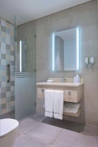 多哈Hampton By Hilton Doha Old Town的带淋浴、盥洗盆和镜子的浴室