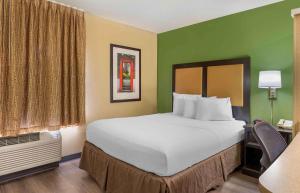 梅里尔维尔梅里尔维尔美国长住酒店- 美国路30号的一张大床,位于酒店带绿色墙壁的房间里