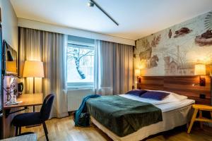 于默奥北欧于默奥南酒店的一间卧室配有一张床、一张书桌和一个窗户。