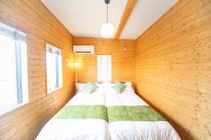 KusumotoAwaji Seaview Resort in Nojima的木墙和窗户的客房内的一张床位
