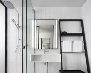 堪培拉Little National Hotel Canberra的浴室配有盥洗盆和带镜子的淋浴