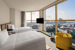 河内L7 WEST LAKE HANOI By LOTTE的酒店客房设有两张床和大窗户。