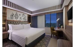 日惹The Alana Hotel & Conference Center Malioboro Yogyakarta by ASTON的一间卧室配有一张床、一张书桌和一个窗户。