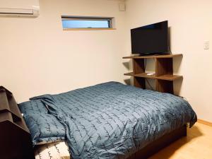 东京K.House的一间卧室配有一张床和一台平面电视