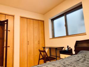 东京K.House的一间卧室配有一张床、一张书桌和一个窗户。