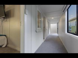 WhangaroaFISHERMANS’DELIGHT的房屋内带白色墙壁和窗户的走廊