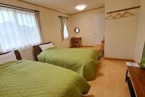 高山ホリデーハウス慈野(ジノ)的配有绿色棉被的客房内的两张床