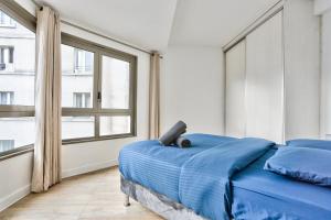 巴黎Appartement Quartier Republique的一间卧室设有蓝色的床和大窗户