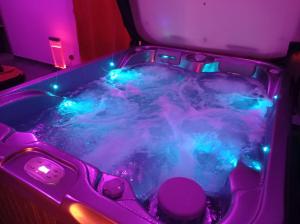 DamprichardParadis Secret Spa的客房内的热水浴池配有蓝色和紫色的灯