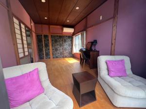 大岛田园之家度假屋的客厅配有两把白色椅子和紫色墙壁