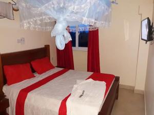 姆特瓦帕Hotel Basilea Mtwapa的一间卧室配有一张带红色窗帘的床和一扇窗户