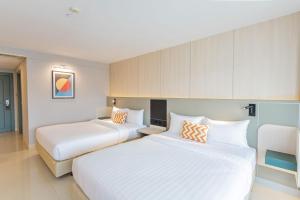 慕斯Lacol Khao Yai - A Chatrium Collection的配有2张床铺的酒店客房,提供白色床单和橙色枕头