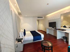 穆扎夫法尔普尔The Emerald Hotel & Siya Milan Banquets的酒店客房配有一张床、一张书桌和一台电视。