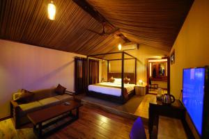 瓦亚纳德Niyatma Wayanad Premium Coffee Resort By VOYE HOMES的一间卧室配有一张床、一张沙发和一台电视。