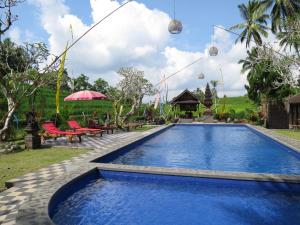 塔巴南Kebun Villa, Belimbing, Bali的一个带桌椅的度假村游泳池