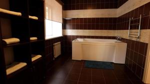 库斯塔奈Hotel Fessla的浴室设有白色浴缸和棕色瓷砖