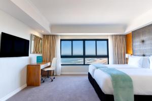 布鲁堡史特兰Blaauwberg Beach Hotel的酒店客房配有一张床、一张书桌和一台电视。