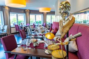 OberorkeHotel Freund - Privathotels Dr Lohbeck的中间设有餐桌和雕像的用餐室
