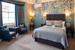 吉尔福德Mandolay Hotel Guildford的一间卧室配有一张大床和两把椅子