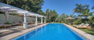 内罗毕内罗毕海明威酒店的毗邻度假酒店的带椅子和遮阳伞的游泳池