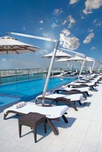 迪拜瑞吉斯公园克里斯金酒店的游泳池旁的一排躺椅和遮阳伞