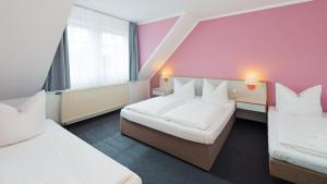 Hormersdorf黑姆斯多夫汽车旅馆的酒店客房设有两张床和粉红色的墙壁。