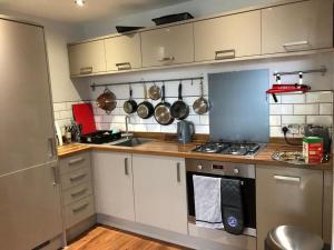 基督城Charming 2-Bed Apartment in Christchurch的厨房配有白色橱柜以及带锅碗瓢盆的炉灶。