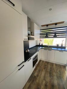 米德尔哈尼斯Het Dirkbosje的厨房铺有木地板,配有白色橱柜。