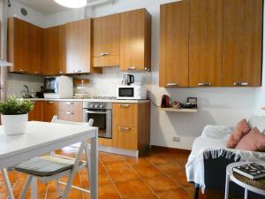 圣佩莱格里诺温泉Baciati dal Sole-Self check-in的厨房配有木制橱柜和白色的桌椅