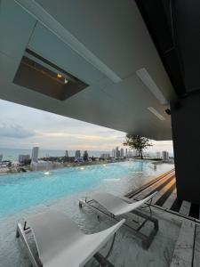 芭堤雅市中心Once Pattaya的一个带椅子的游泳池,享有城市美景