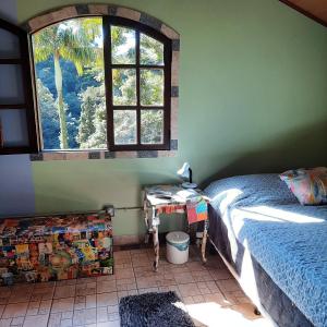 圣佩德罗塞拉Suítes Casinha do Alto da Bocaina的一间卧室配有一张床和一张带窗户的书桌