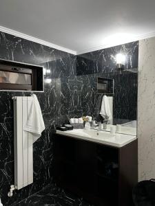 MineriCasa moderna in Mineri的一间带水槽和黑色大理石墙的浴室