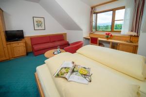 彭茨贝格Landhotel Hoisl-Bräu的酒店客房,配有一张床和一张红色的沙发