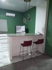 Augi's Rental的厨房配有白色柜台和2张红色凳子