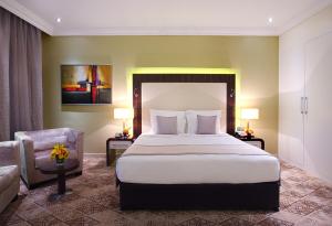 迪拜Elite Byblos Hotel的配有一张床和一把椅子的酒店客房