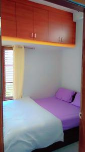 迈索尔Kailash Guest Home的小型客房配有2张床铺和木制橱柜。