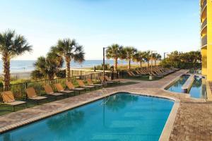 默特尔比奇Hilton Grand Vacations Club Anderson Ocean Myrtle Beach的一个带椅子的游泳池和海滩