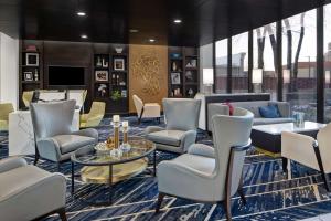 俄克拉何马城埃姆布里奇酒店集团俄克拉何马城塔楼酒店的大堂设有椅子、桌子和电视。