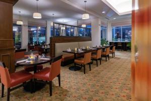 Devens德文斯康门希尔顿花园酒店的用餐室设有桌椅和窗户。