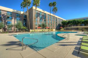 凤凰城凤凰城北希尔顿逸林酒店的棕榈树建筑前的游泳池