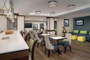 蒙罗维尔匹兹堡门罗维尔希尔顿恒庭酒店的餐厅设有桌椅和沙发。