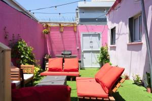 特拉维夫Ajami Guest House的一个带红色椅子和粉红色墙壁的庭院