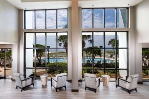 奥兰治比奇The Island House Hotel a Doubletree by Hilton的一个带窗户和椅子的大堂以及一个游泳池