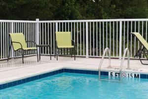 沃尔特伯勒Hampton Inn & Suites Walterboro的一个带两把椅子和围栏的游泳池