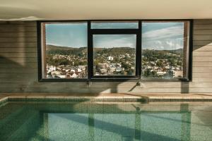 坦迪尔Mulen Hotel Tandil的游泳池,从窗户可欣赏到城市美景