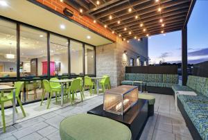 达拉姆Home2 Suites By Hilton Raleigh Durham Airport RTP的餐厅设有绿色的椅子和桌子以及窗户。