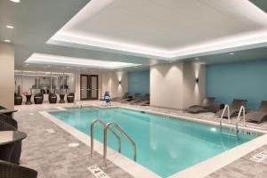 罗切斯特Hilton Garden Inn Rochester - University & Medical Center的游泳池位于酒店客房内,配有桌椅