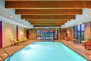 罗切斯特Home2 Suites by Hilton Rochester Mayo Clinic Area的酒店大堂的游泳池,配有桌椅