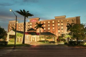 迈尔斯堡迈尔斯堡机场/FGCU希尔顿花园酒店的一条街道前方棕榈树的大型酒店