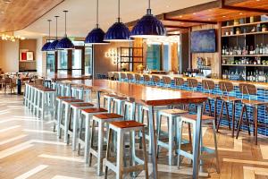 圣地亚哥Hilton Garden Inn San Diego Downtown/Bayside, CA的餐厅内带木桌和凳子的酒吧